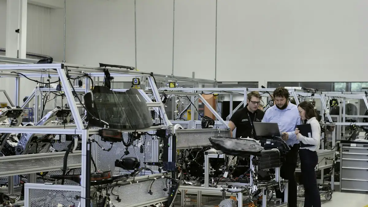 Three engineers reviewing a laptop together between assembly stations in a bright factory hall