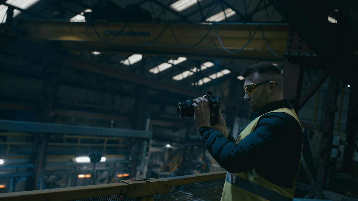A man in safety glasses and a high-visibility vest photographs equipment inside a large industrial hall