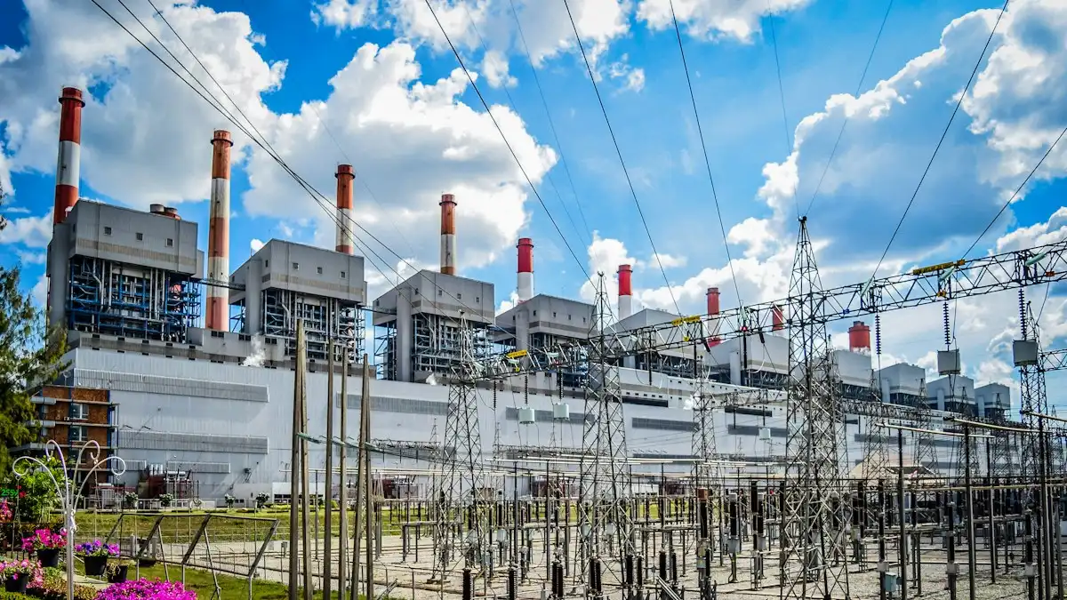 Power station with red and white chimneys behind a switchyard of transmission towers and power lines