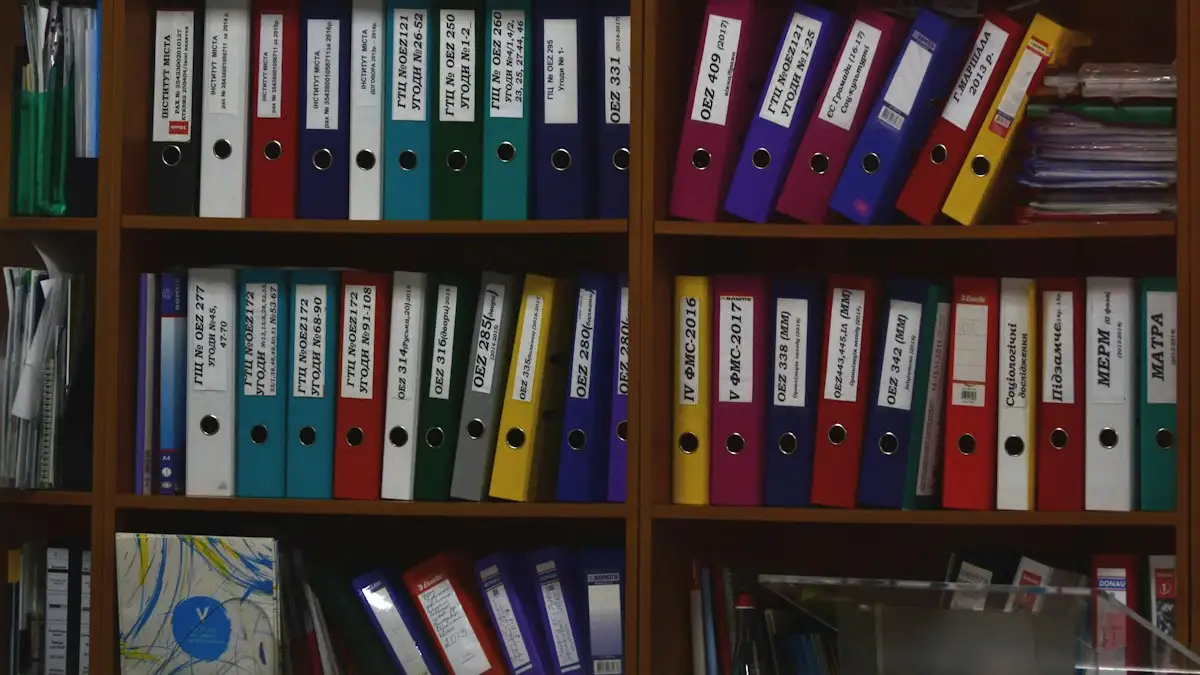 Rows of coloured ring binders with labelled spines on wooden office shelves