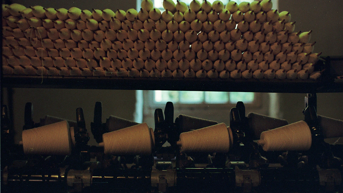 Cones of white yarn stacked on a shelf above a row of yarn cones on a textile machine